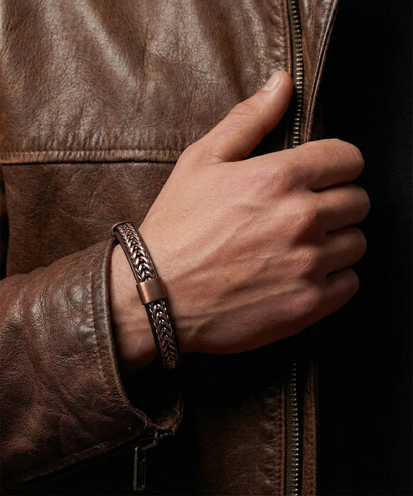 Close-up of bronze-tone chain and leather bracelet