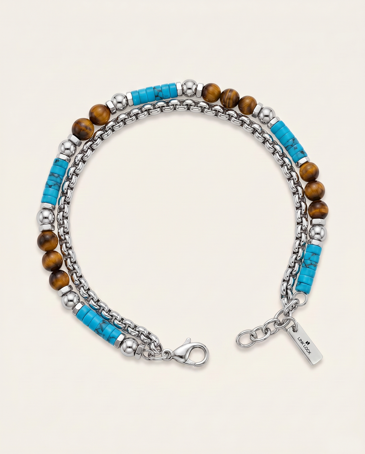 A double-strand beaded bracelet featuring silver-tone chain links, polished brown tiger's eye beads, and bright turquoise blue cylindrical beads, with a lobster clasp and a small hanging brand tag on a light beige background.