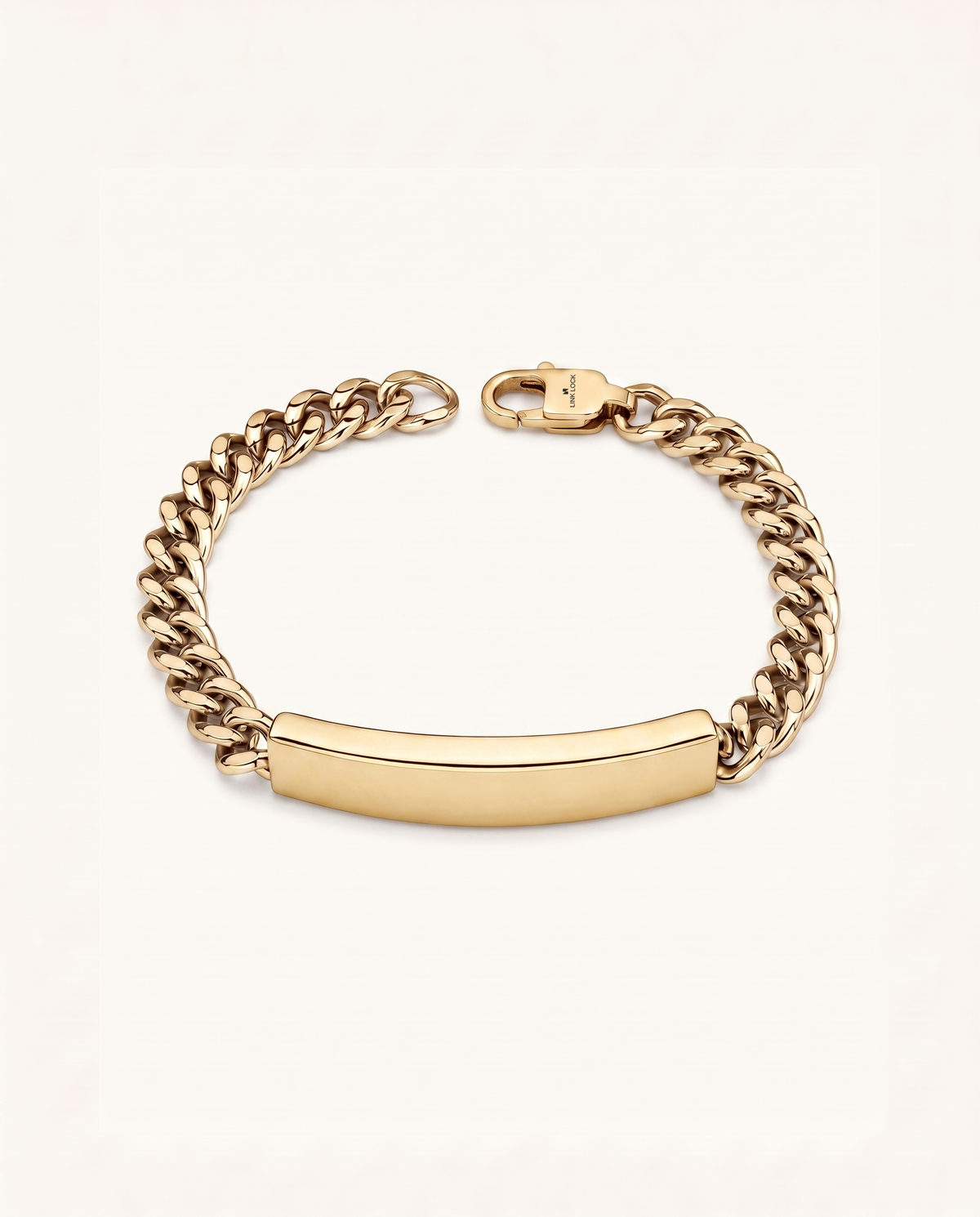 A gold-tone chain bracelet with a smooth, curved ID bar and a lobster clasp, displayed on a clean off-white background.