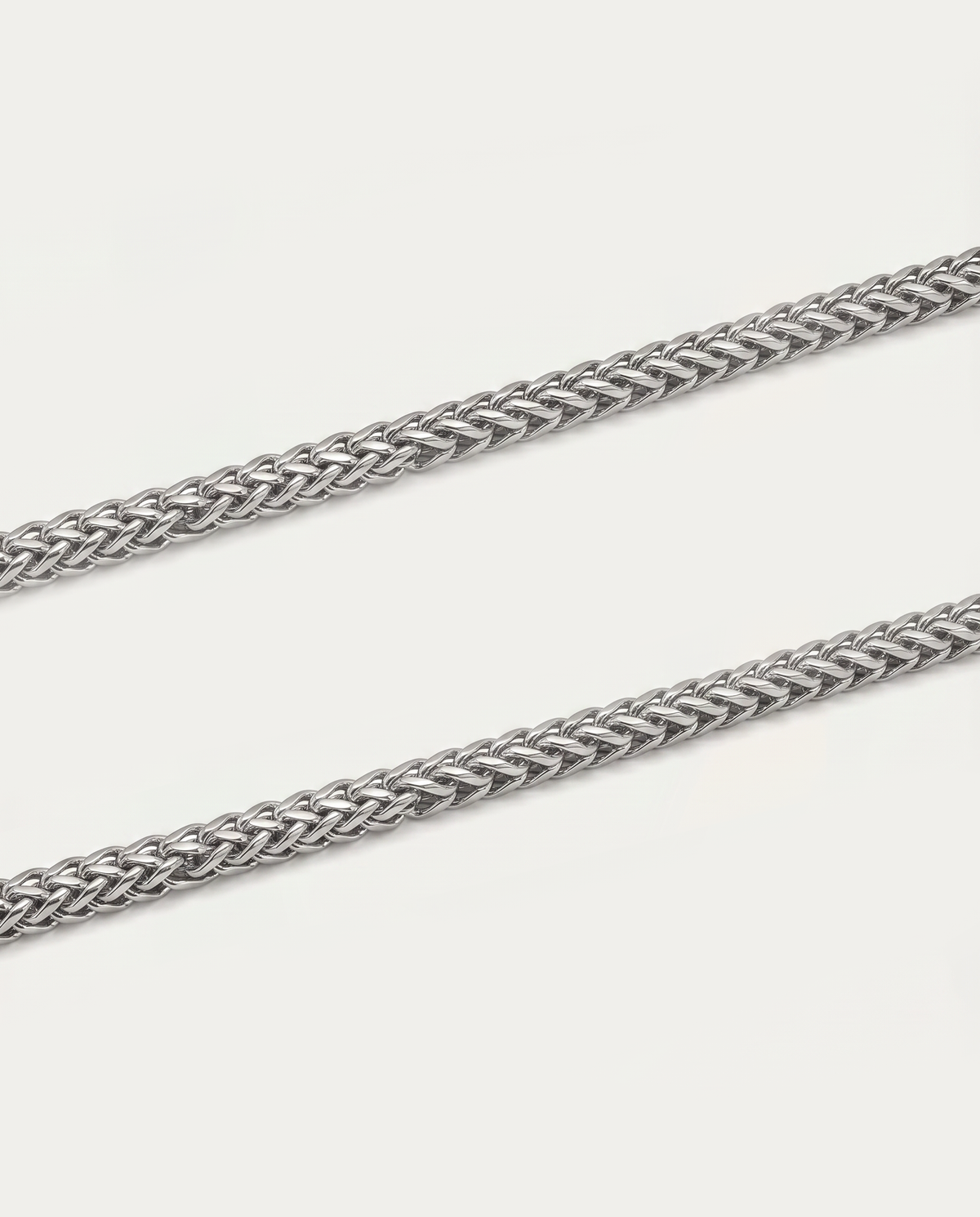 A close-up of a silver-toned braided chain strap, likely for eyeglasses or jewelry, shown diagonally on a light off-white background.