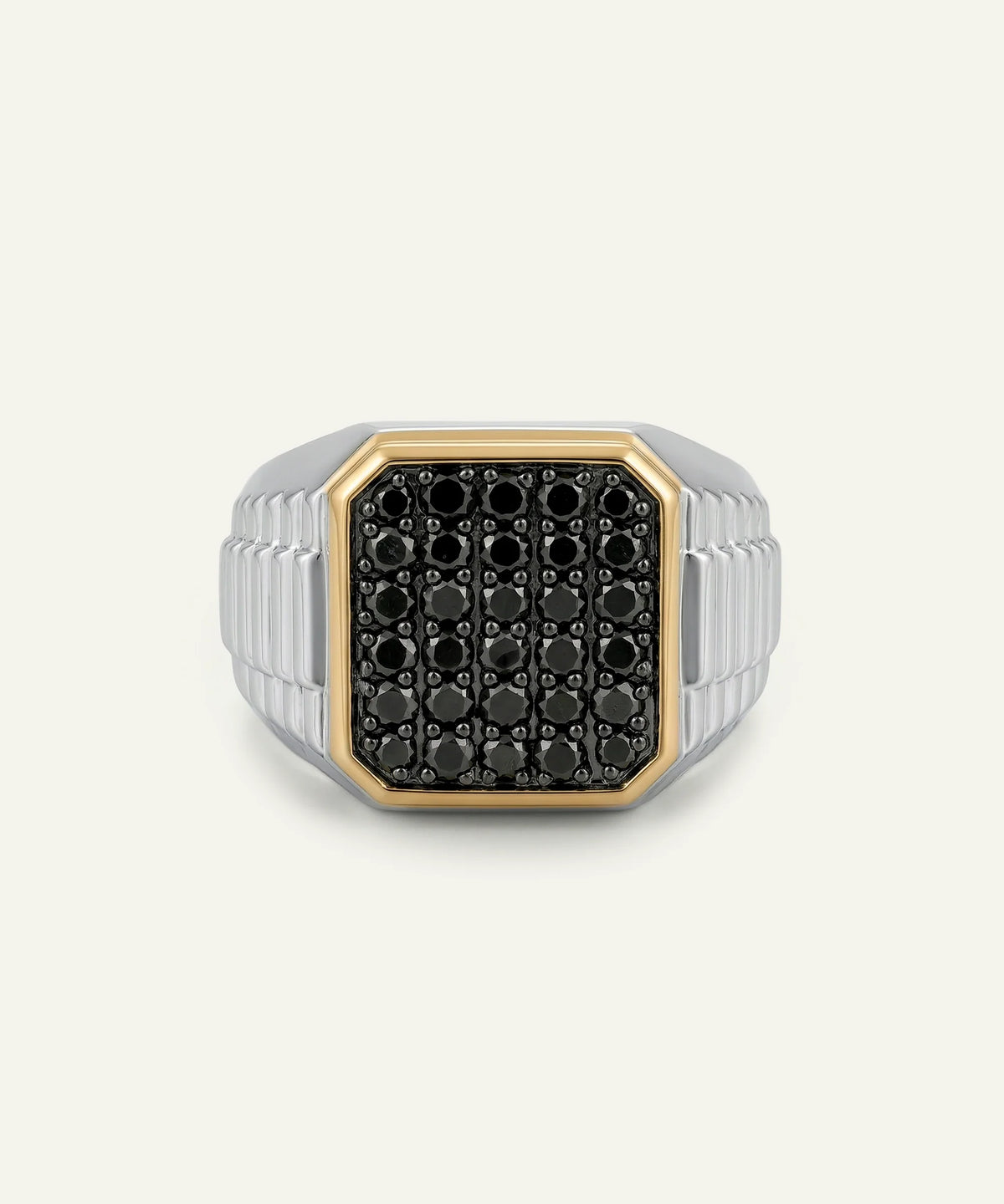 A men's signet ring featuring a black pavé face with a gold bezel, set on a silver-toned ribbed band, shown against a light off-white background.