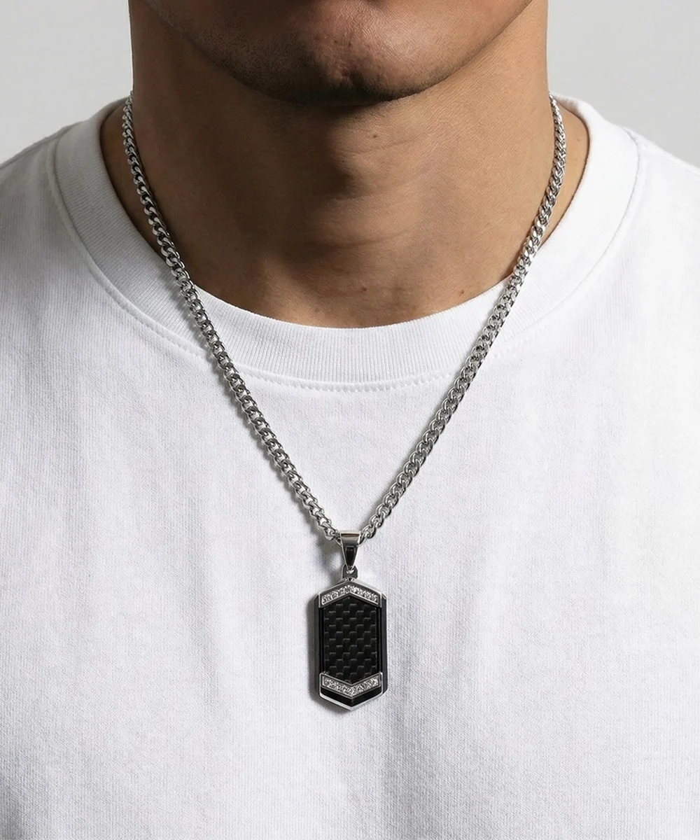 Person wearing a silver chain necklace with a black pendant on a white background
