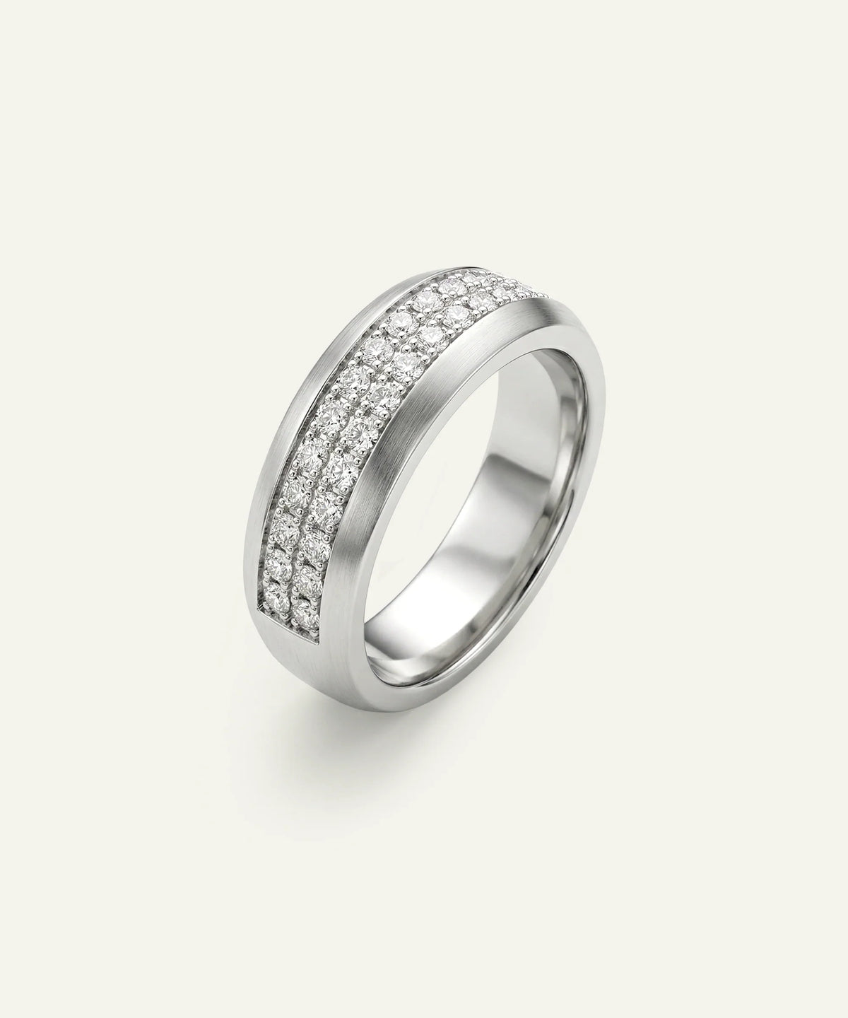 A silver-toned band ring featuring two parallel rows of small clear pavé stones on a light cream background.