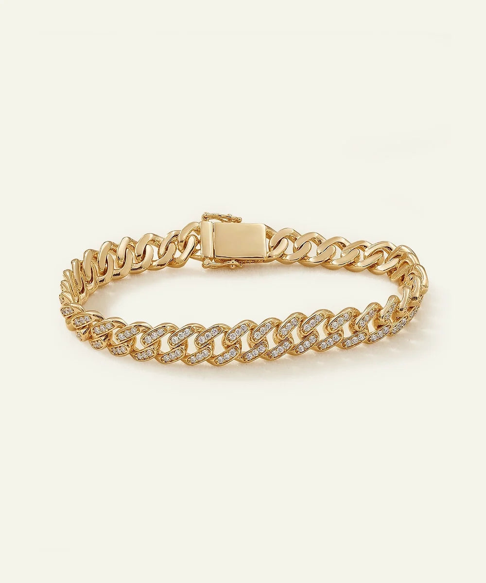 A gold-toned pavé diamond-encrusted Miami Cuban link bracelet featuring a smooth, polished box clasp center, set against a light cream background.