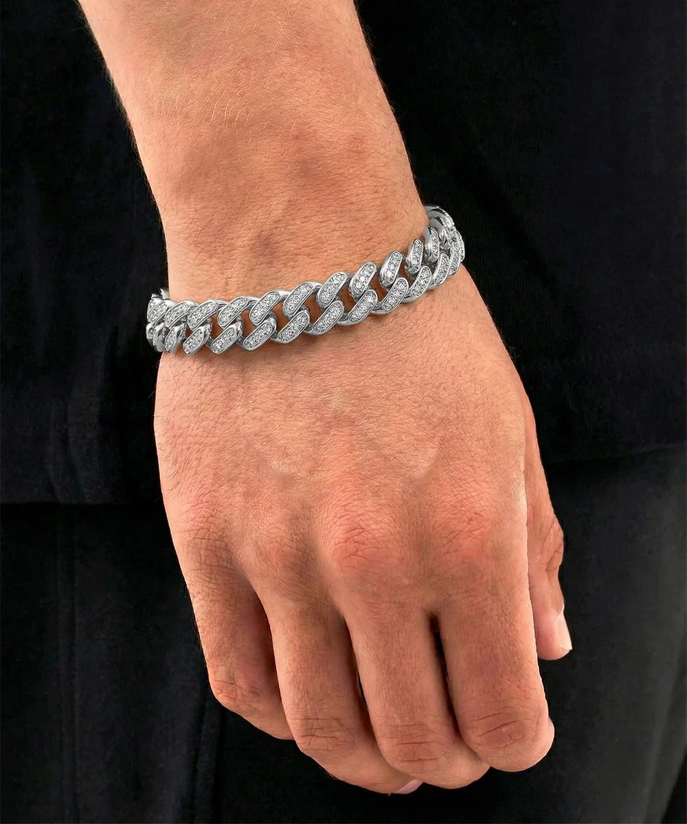 Close-up lifestyle shot of a man's hand and wrist wearing a silver-toned pavé diamond-encrusted Miami Cuban link bracelet, styled against a black shirt background.