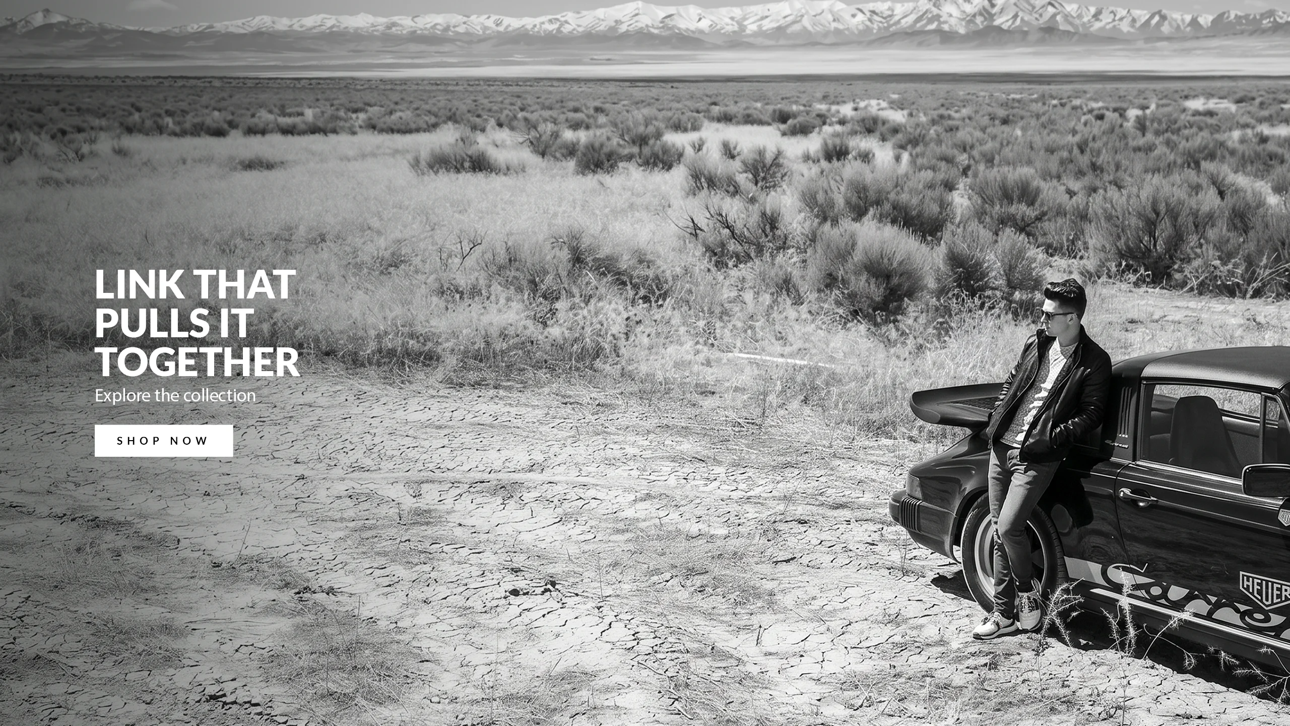 Man standing beside a black car in a desert landscape